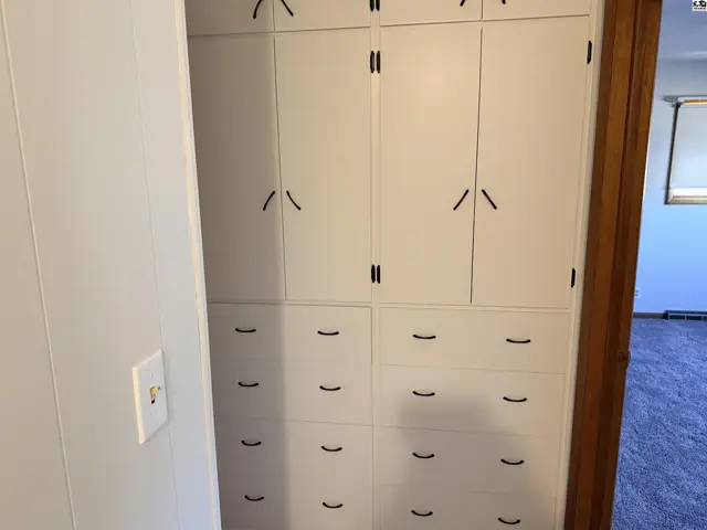 Built-in white cabinetry with multiple drawers and doors offers ample storage.