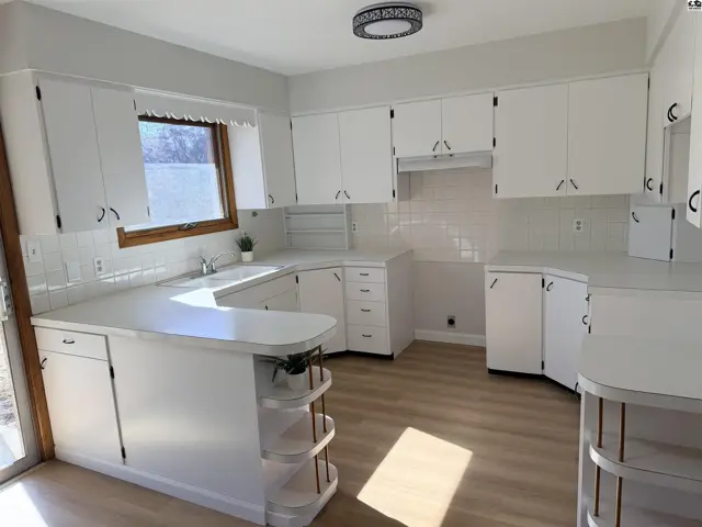 White cabinetry and countertops define this spacious kitchen with a large window.