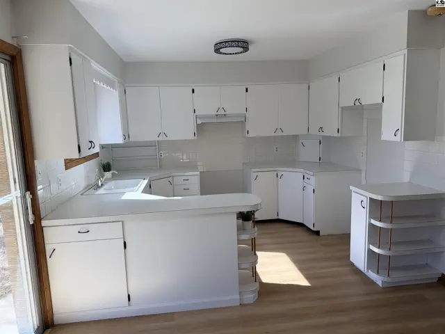White cabinets and countertops line this spacious kitchen with a built-in island.