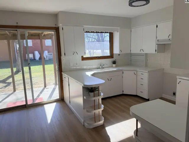White cabinets and countertops accent this kitchen with a sliding glass door.