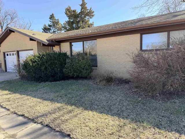 Brick home with attached two-car garage and mature landscaping.