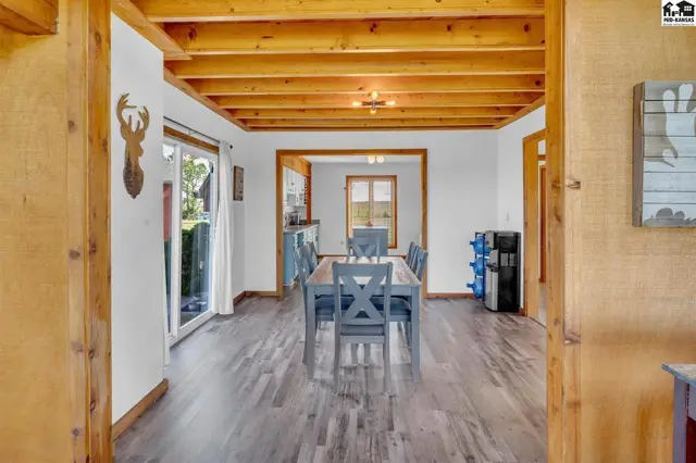 Spacious dining room with wood-beamed ceiling, gray furniture, and wood-look flooring.