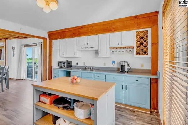 Bright kitchen with white cabinets, blue base cabinets, butcher block island, and wooden beams.