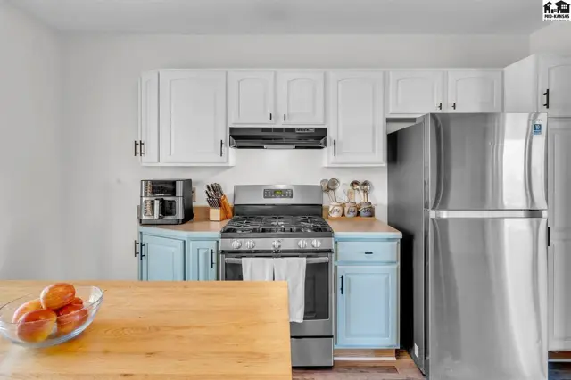 Modern kitchen with stainless steel appliances, white cabinets, and light blue base cabinets.