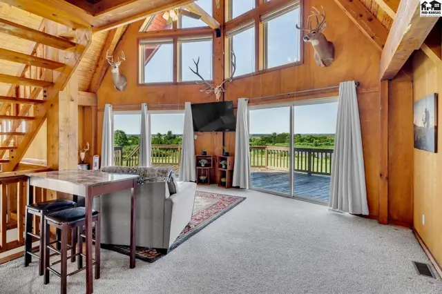 Spacious living room with vaulted wood ceilings, large windows, and scenic country views.