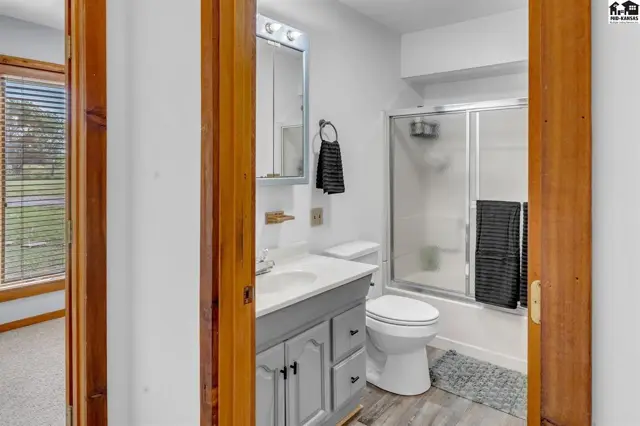 Modern bathroom with gray vanity, white toilet, and glass-enclosed shower.