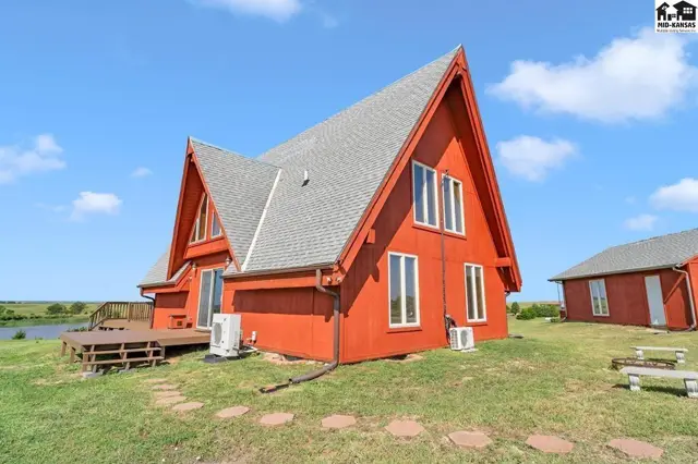 Bright red A-frame home with a deck and detached garage sits on a grassy lot.