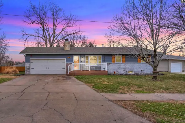 Blue ranch home with white trim, garage, and wood accents under a colorful twilight sky.