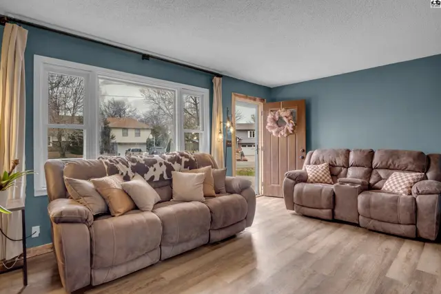 Cozy living room with plush recliners, large windows, and light wood floors.