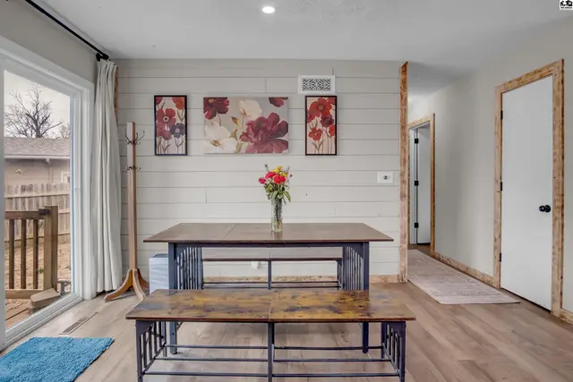 Dining area with shiplap walls, wood floors, and a table with a bench.