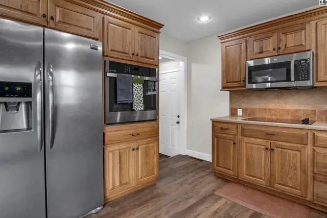 Spacious kitchen features stainless steel appliances, warm wood cabinetry, and granite countertops.