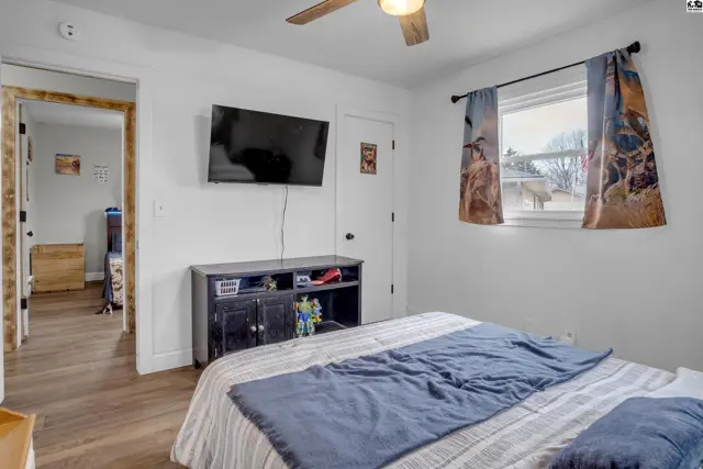 Bedroom with a bed, TV, dark wood media console, and a window with patterned curtains.