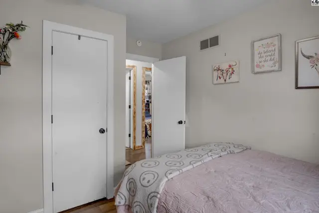Bedroom with light gray walls, white doors, and a pink comforter on the bed.