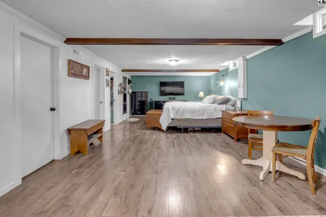 Spacious studio with wood-look flooring, teal accent wall, and a dining table.