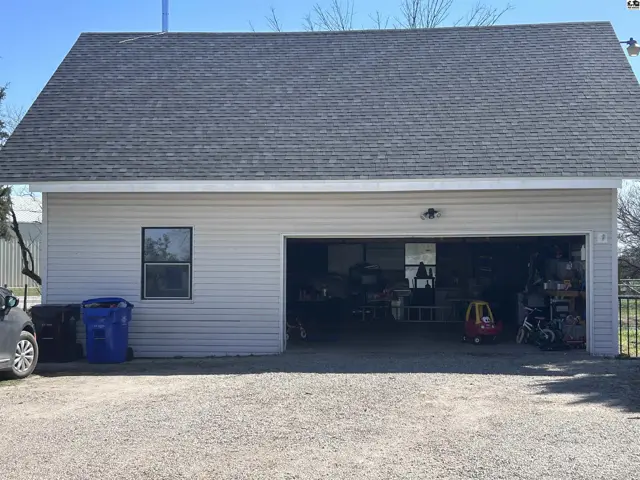 Two-car garage with light gray siding, a single window, and gravel driveway.