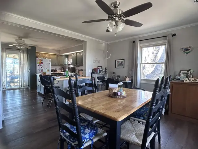 Dining area with wood table and chairs opens to a kitchen with gray cabinets and island.