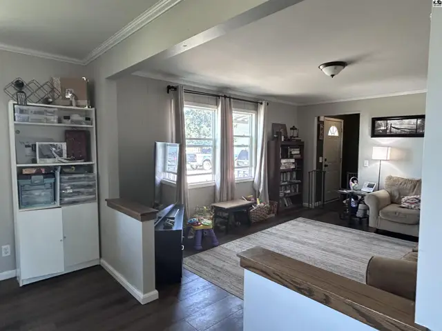 Living room with neutral walls, dark wood floors, and a large white shelving unit.