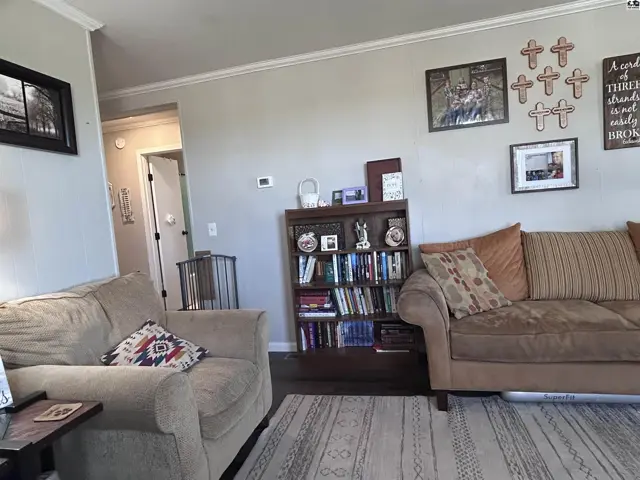 Cozy living room with neutral-toned sofas, a bookshelf, and decorative wall art.