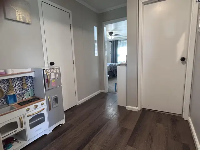 Hallway with gray walls, wood-look flooring, and a children's play kitchen.