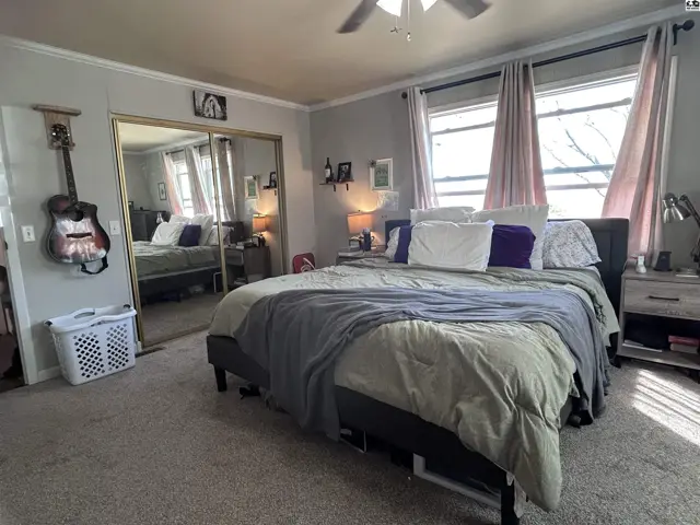 Spacious bedroom with a king-size bed, mirrored closet doors, and large windows with light pink curtains.