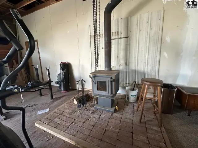 Rustic living space with a wood-burning stove on a brick hearth, exercise equipment, and wooden accents.