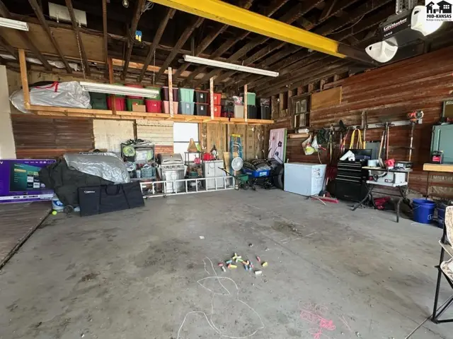 Spacious, unfinished garage with concrete floor, wood paneled walls, and ample storage.