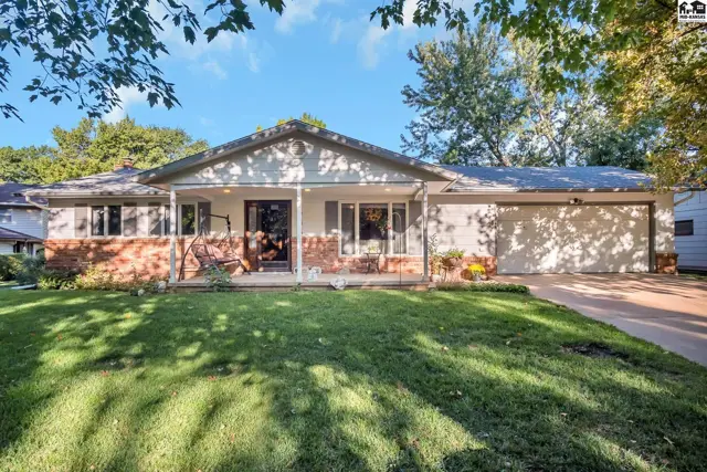 Ranch-style home with brick accents, a covered porch, and a two-car garage on a sunny day.