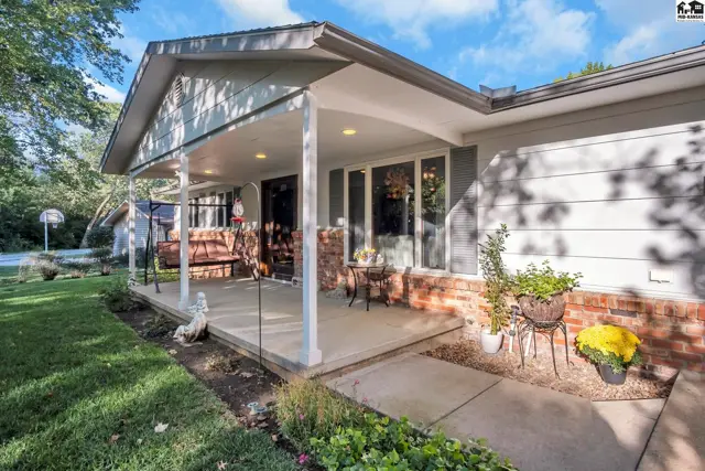 Covered front porch with brick accents, white columns, and seating, leading to a light-filled entryway.