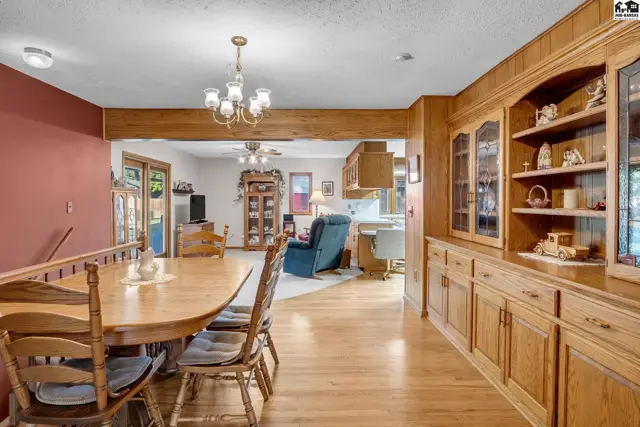 Warm oak cabinetry and a dining set complement the open-concept living and kitchen area.