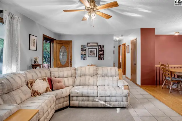 Spacious living room with a large sectional sofa, tiled floor, and wood accents.