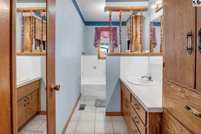 Spacious bathroom with dual vanities, white tile floors, and a soaking tub.