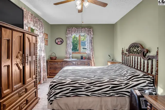 Spacious bedroom with a wooden headboard, zebra-print bedding, and a large wooden dresser.