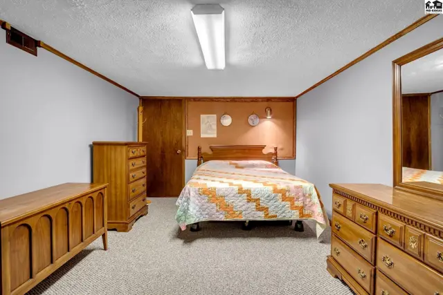 Bedroom with wood furniture, a quilt-covered bed, and light blue walls.