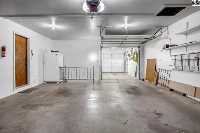 Spacious, clean garage with concrete floors, white walls, and an open overhead door.