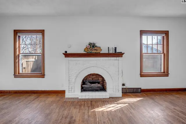 Living room with white brick fireplace, arched opening, and hardwood floors.