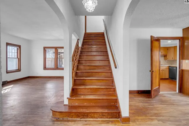 Warm wood staircase and floors complement the bright, airy interior with arched doorways.