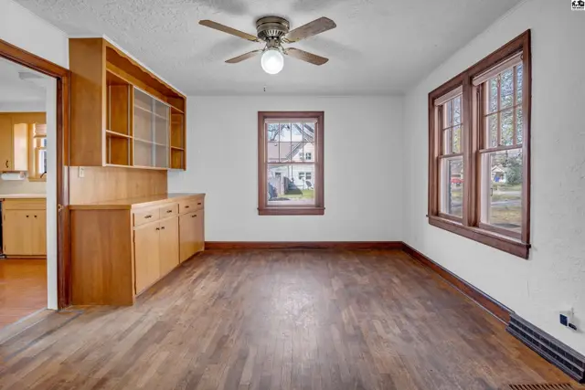Spacious dining room with dark hardwood floors, built-in cabinetry, and wood-trimmed windows.