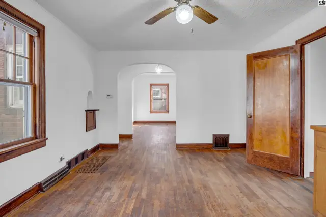Spacious living room with hardwood floors, arched doorway, and natural wood trim.