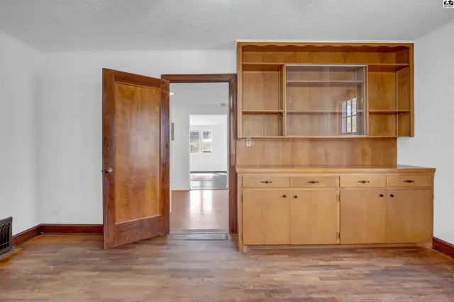 Built-in wooden hutch with glass-fronted cabinets complements the warm wood floors and door.