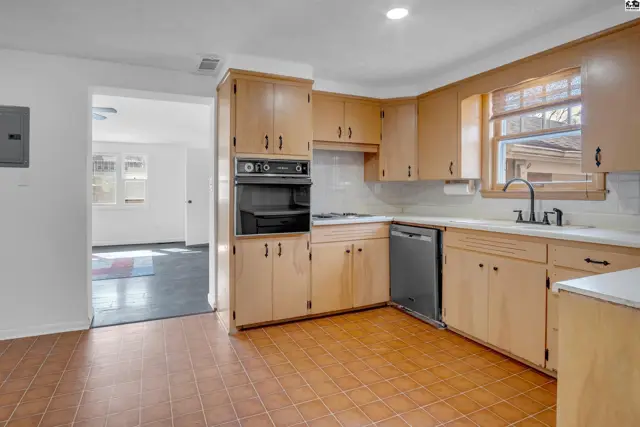 Spacious kitchen with light wood cabinets, white countertops, stainless steel appliances, and tile flooring.