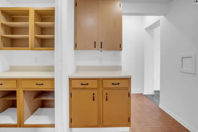Kitchen with light wood cabinets, laminate countertops, and open shelving.