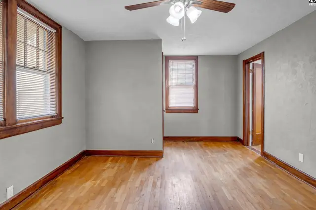 Spacious room with light gray walls, hardwood floors, and warm wood trim.