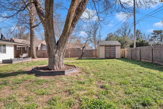 Spacious backyard with a large tree, wooden fence, and a detached shed.
