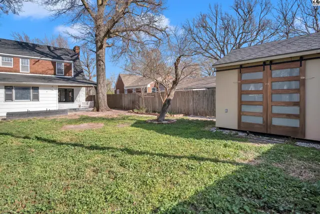 Spacious backyard with a charming shed featuring rustic wooden barn doors.