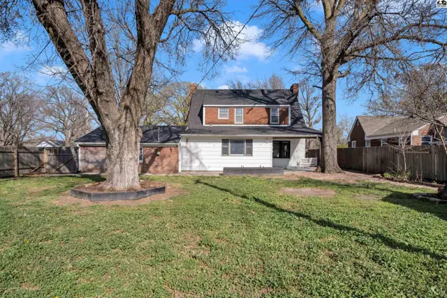 Spacious backyard with mature trees, a white-sided home, and a brick chimney.