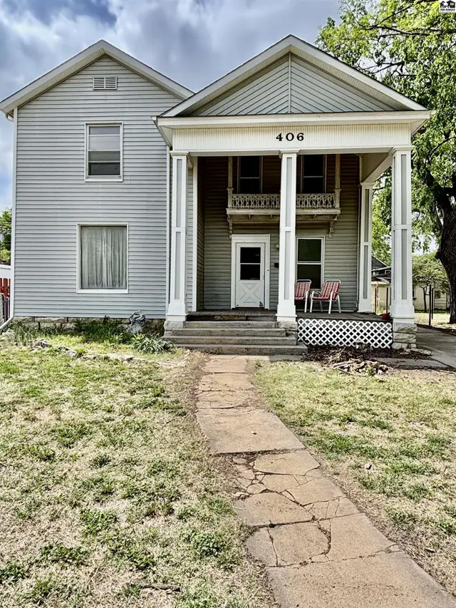 Classic two-story home with a prominent covered porch featuring white columns and a balcony.