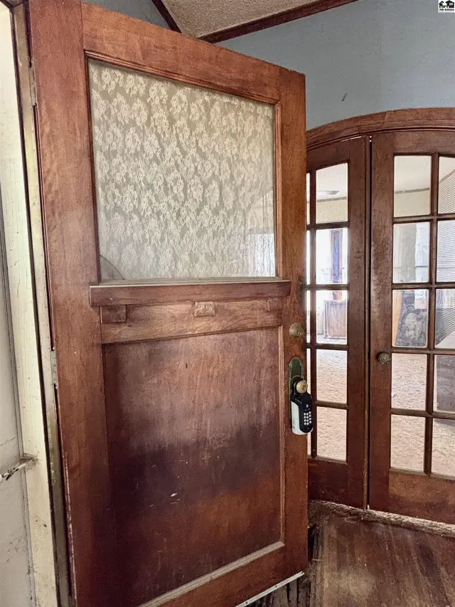 Antique wooden door with patterned glass panel and adjacent arched French doors.