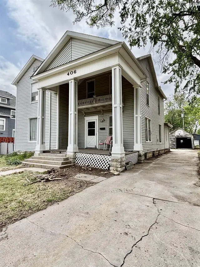 Classic two-story home with a prominent covered porch, white columns, and vinyl siding.