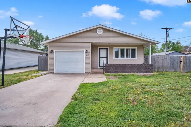 Tan vinyl-sided ranch home with a single-car garage, brick accents, and a basketball hoop.