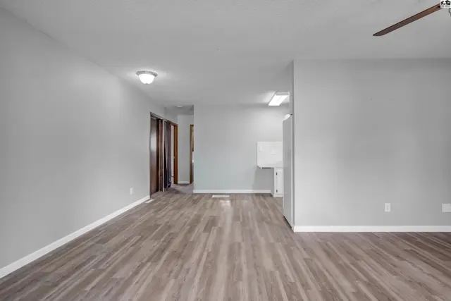 Spacious living area with light gray walls, wood-look flooring, and ceiling lights.